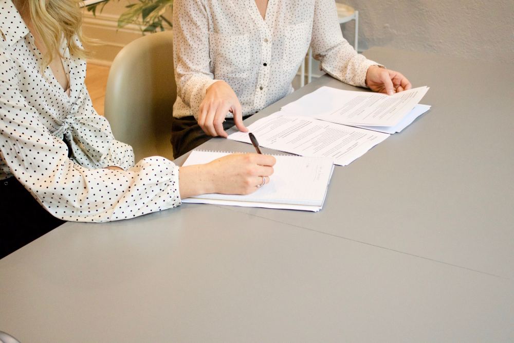 two people writing on a document